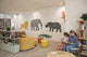 Children's room with large animal murals on the wall, a woman and child reading, and furniture.