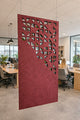 Red decorative screen in an office setting with people working at desks.